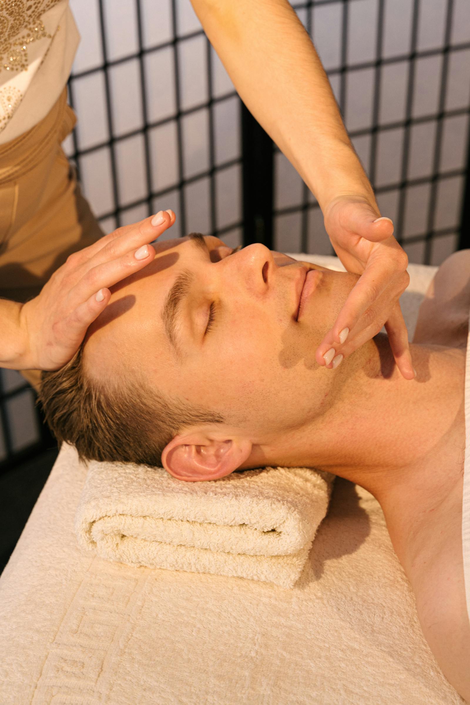 Soin du visage homme en cabine — mains sur le visage masculin